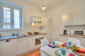 A modern kitchen with white cabinets, a built-in oven, a microwave, and a dining area with a table set for two. - Bellinzona in centro, Bellinzona, Switzerland (Bellinzona)