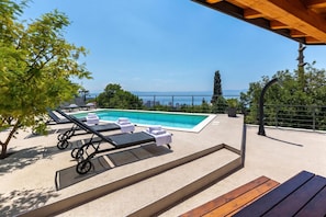 A poolside area with lounge chairs and a view of the sea. - Pool And Garden Apartment Happy Sound, Rijeka, Croatia (Rijeka)