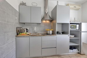 A modern kitchen with grey cabinetry, a stainless steel range hood, and a built-in oven. - Pool And Garden Apartment Happy Sound, Rijeka, Croatia (Rijeka)