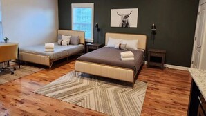 Ein Schlafzimmer mit zwei Betten, einem Schreibtisch und einem Fenster.