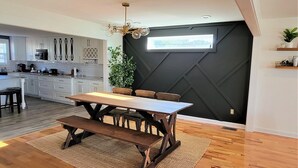 Eine moderne Küche mit weißen Schränken, einem Holztisch und einer Wand in Schwarz mit einem Fenster.