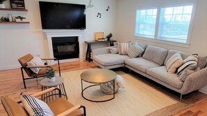 Ein Wohnzimmer mit Ecksofa, Kamin, Fernseher und Deckenventilator.