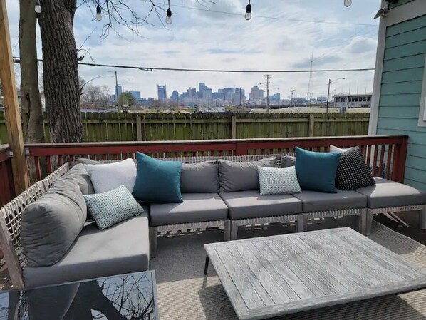 An outdoor seating area with a sofa and a table, overlooking a city skyline.