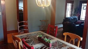 A dining area with a chandelier, a table with a decorative centerpiece, and chairs.