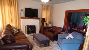 A living room with a fireplace, leather sofas, a blue armchair, and a patterned rug.