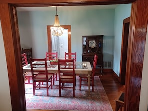 A dining room with a wooden table, red chairs, a chandelier, and a patterned rug. - Historic, Cozy Home in the Heart of Town (Jacksonville)