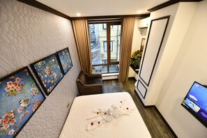 A hotel room with a bed, a TV, a window with curtains, and artwork on the wall. - Kingdom Hotel Hanoi (Hanoi)