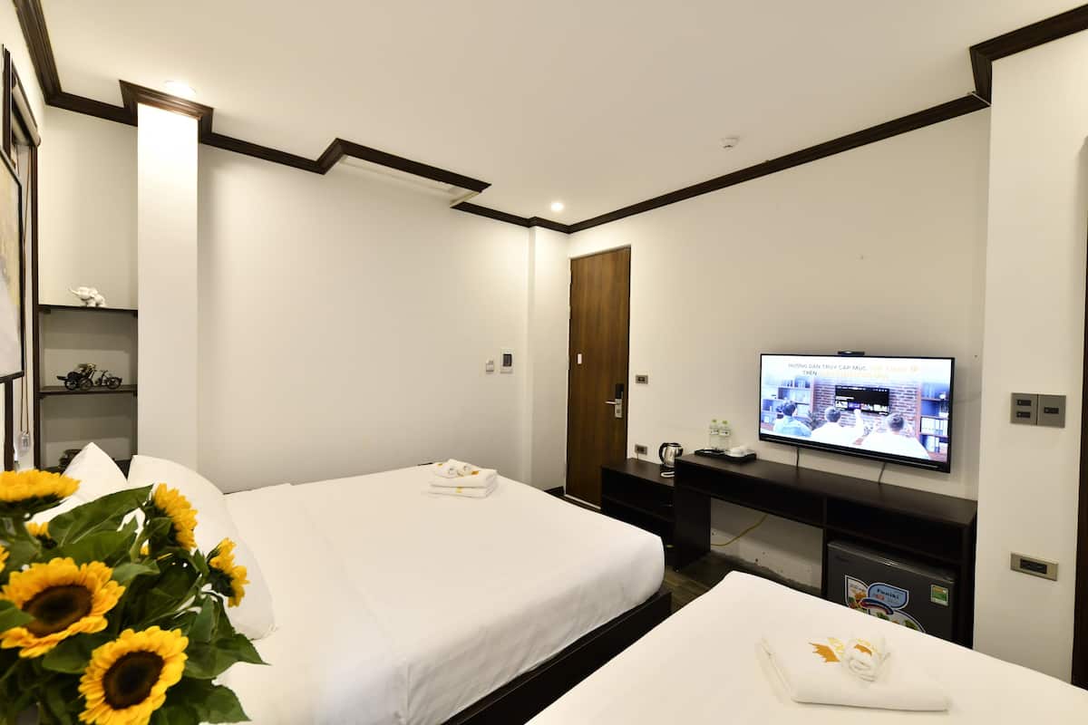 Habitació d'hotel amb dos llits, una televisió, escriptori i televisió penjada a la paret.