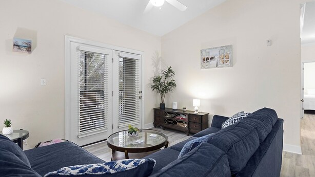 A living room with a dark blue sofa, a glass coffee table, and a ceiling fan. - Near Tropic Falls Water Park – Fun & Relaxation Await! (Foley)