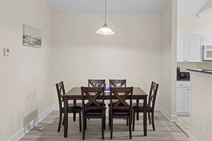 A dining area with a wooden table and chairs, a pendant light, and a kitchen in the background. - Near Tropic Falls Water Park – Fun & Relaxation Await! (Foley)