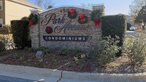 Placa para Park Avenue Condominiums com fachada de tijolos, decoração de grinaldas e caixa de correio na calçada.