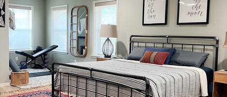 A bedroom with a bed, a ceiling fan, a large rug, and two framed quotes on the wall.