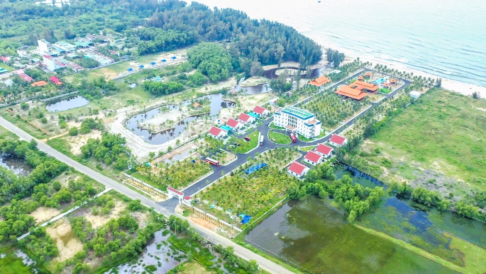 Vista aérea de un resort con varias edificaciones, una piscina y una playa.