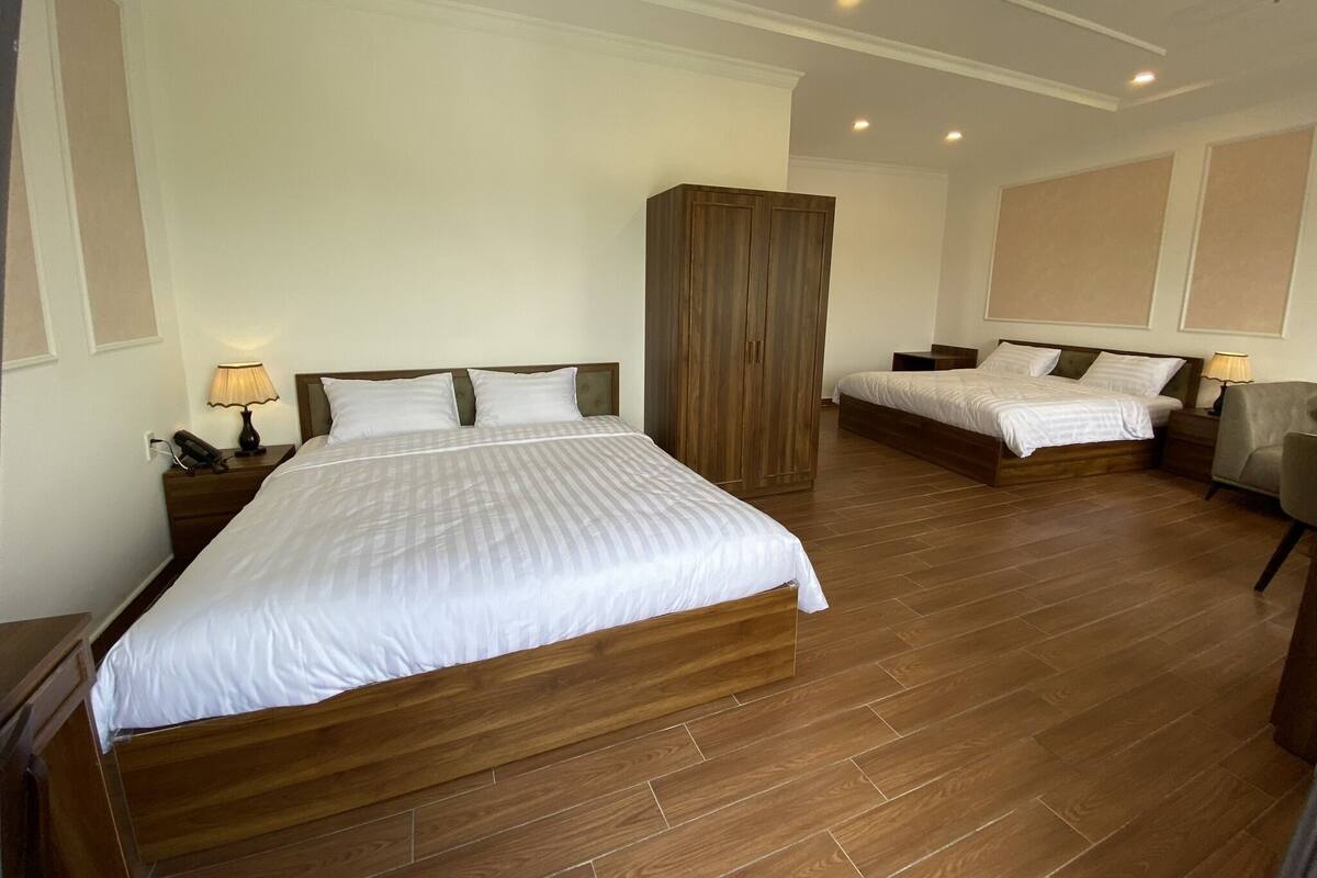 A hotel room with two beds, wooden flooring, and a wardrobe.