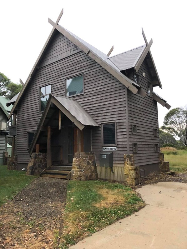 Rustic cabin-style building with a steeply pitched roof and a welcoming front porch.