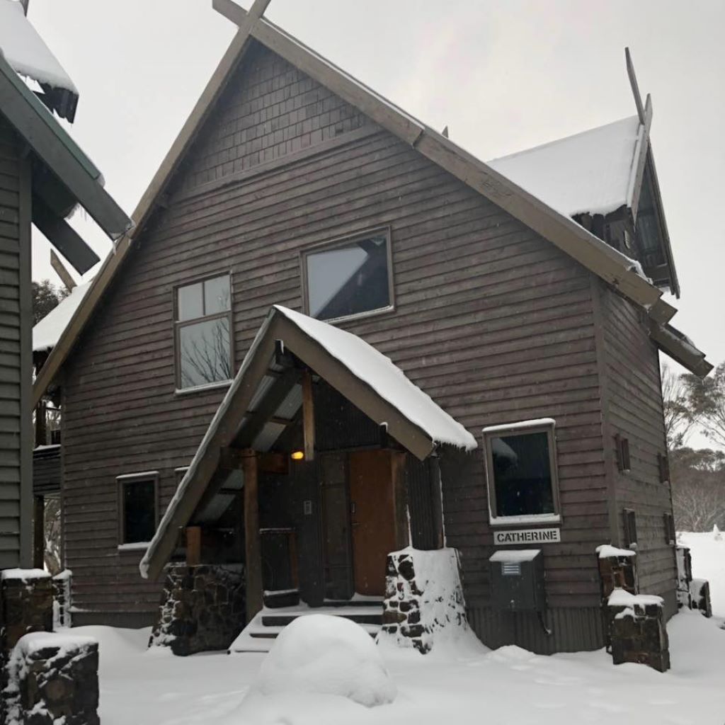 A wooden cabin with a steeply pitched roof, a front porch, and a sign that reads "CATHERINE".