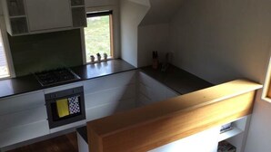 Een moderne keuken met een ingebouwde kookplaat, witte kastjes en een houten aanrecht.