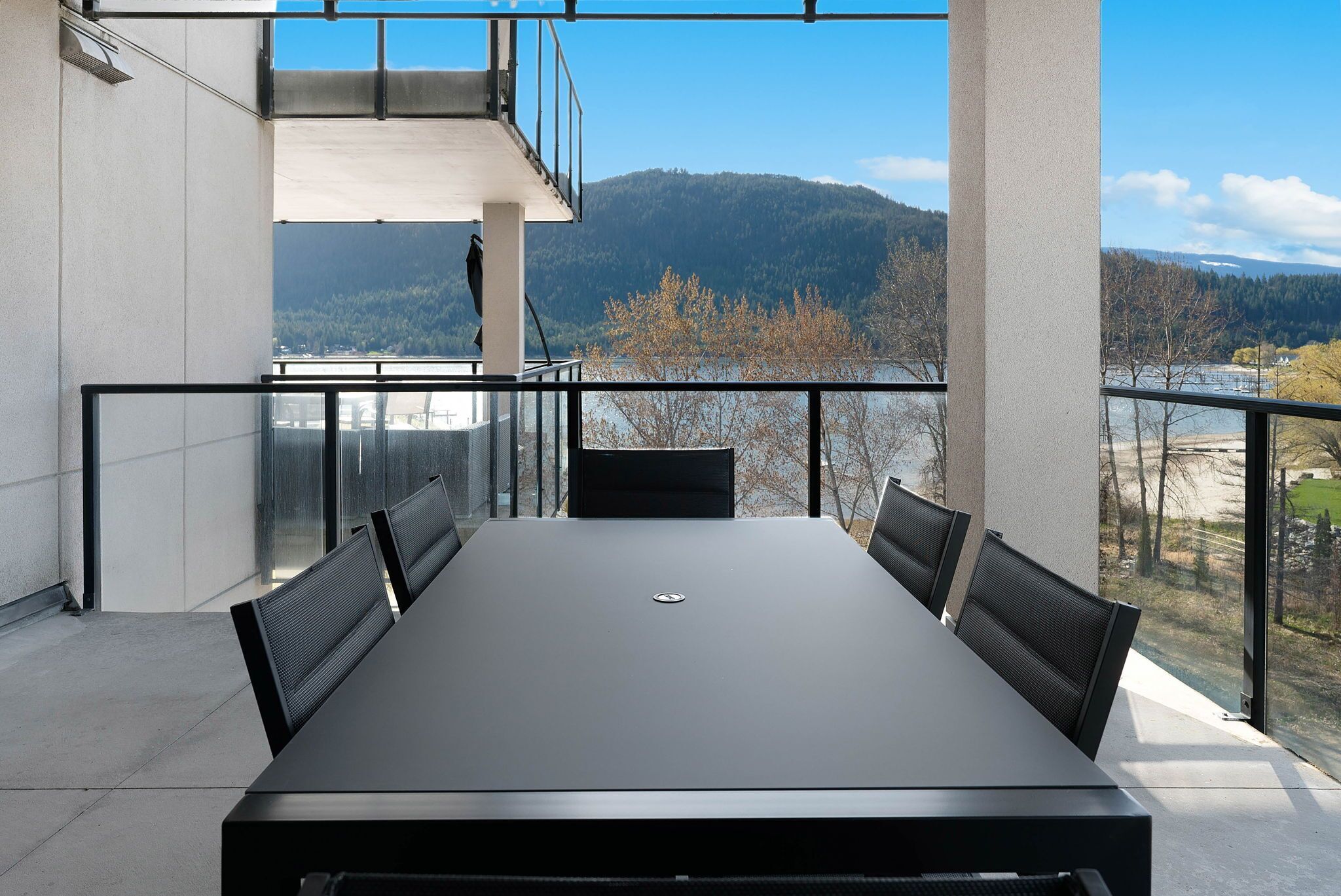 A conference room with a large table and chairs, overlooking a scenic view of mountains and a lake.