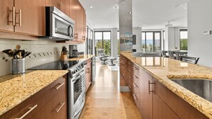 A modern kitchen with granite countertops, stainless steel appliances, and wooden cabinets. - Luxury Condo on Mara Lake with Boat Slip & Pool. (Sicamous)