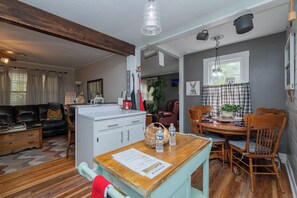 Una sala de estar acogedora con un sofá, una mesa de comedor de madera y una cocina con refrigerador y alacenas.