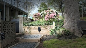 A garden with wooden planters, a barbecue grill, and a tree.