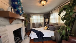 A cozy room with a fireplace, a bed, a sofa, and a large plant.
