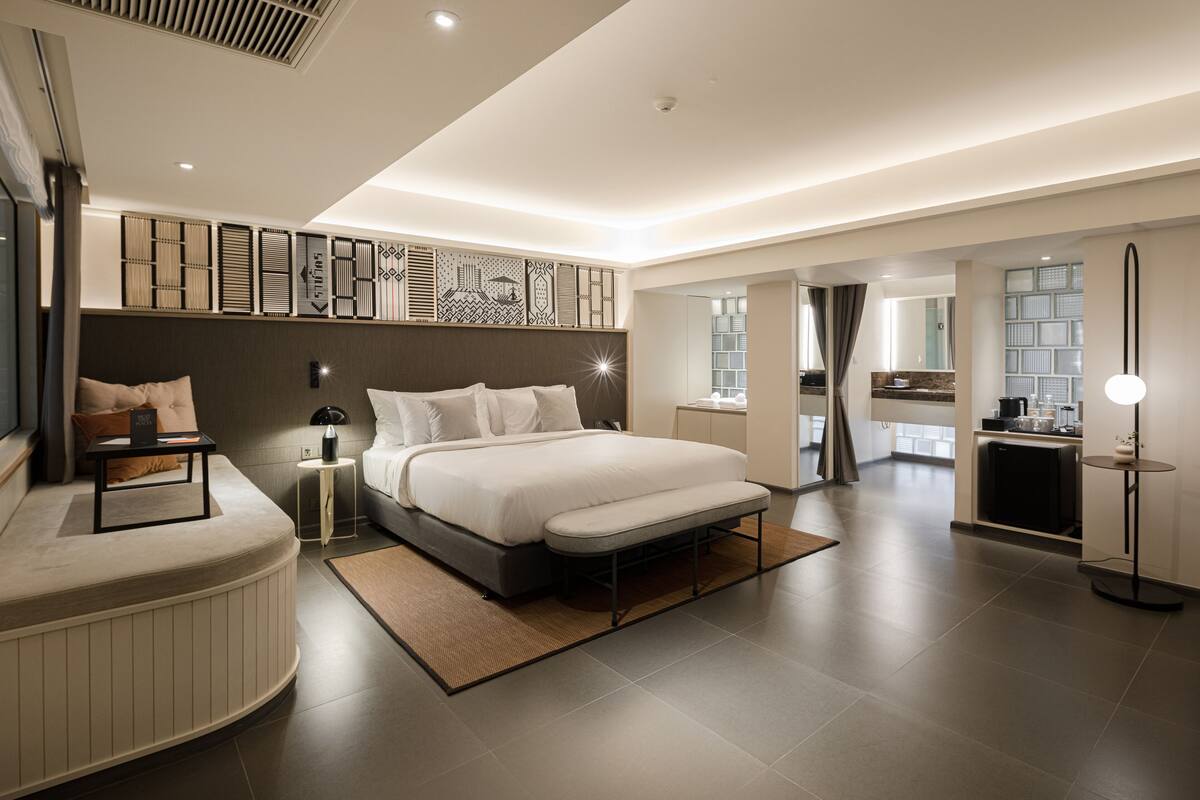 A modern bedroom with a large bed, bedside tables, a nightstand, and a built-in wardrobe.