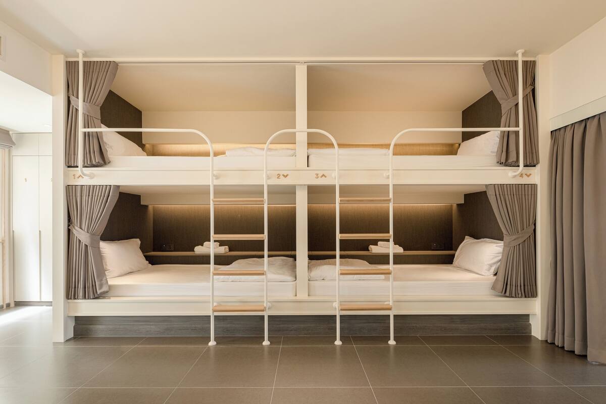 A bunk bed room with a wooden headboard, curtains, and a bedside table.
