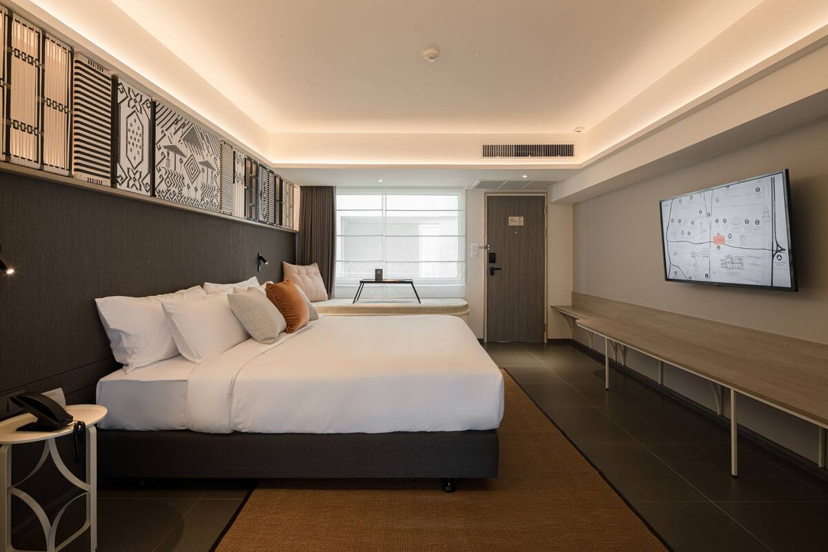 A modern hotel room with a large bed, a desk, and a wall-mounted TV.