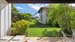 A patio with a table, chairs, and a view of a well-maintained lawn and house. - BRAND NEW AC | Ground Floor 1 Bdrm | Peekaboo Ocean View | Pool | 5 Min to Beach (Koloa)
