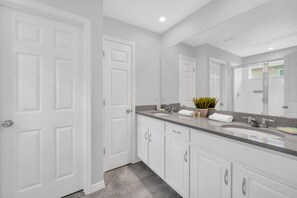 A modern bathroom with white cabinetry, a large mirror, and a granite countertop.
