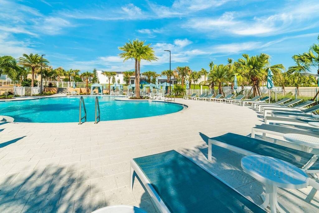 A pool area with lounge chairs and palm trees.