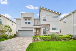 A modern two-story house with a stone accent wall, a front garage, and a well-maintained lawn.
