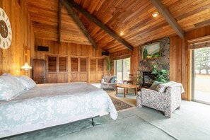 Una habitación amplia con una cama grande, un sofá, una mesita y una chimenea.