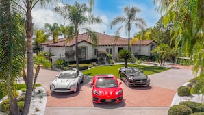 A house with a driveway, three cars, and a well-maintained lawn.