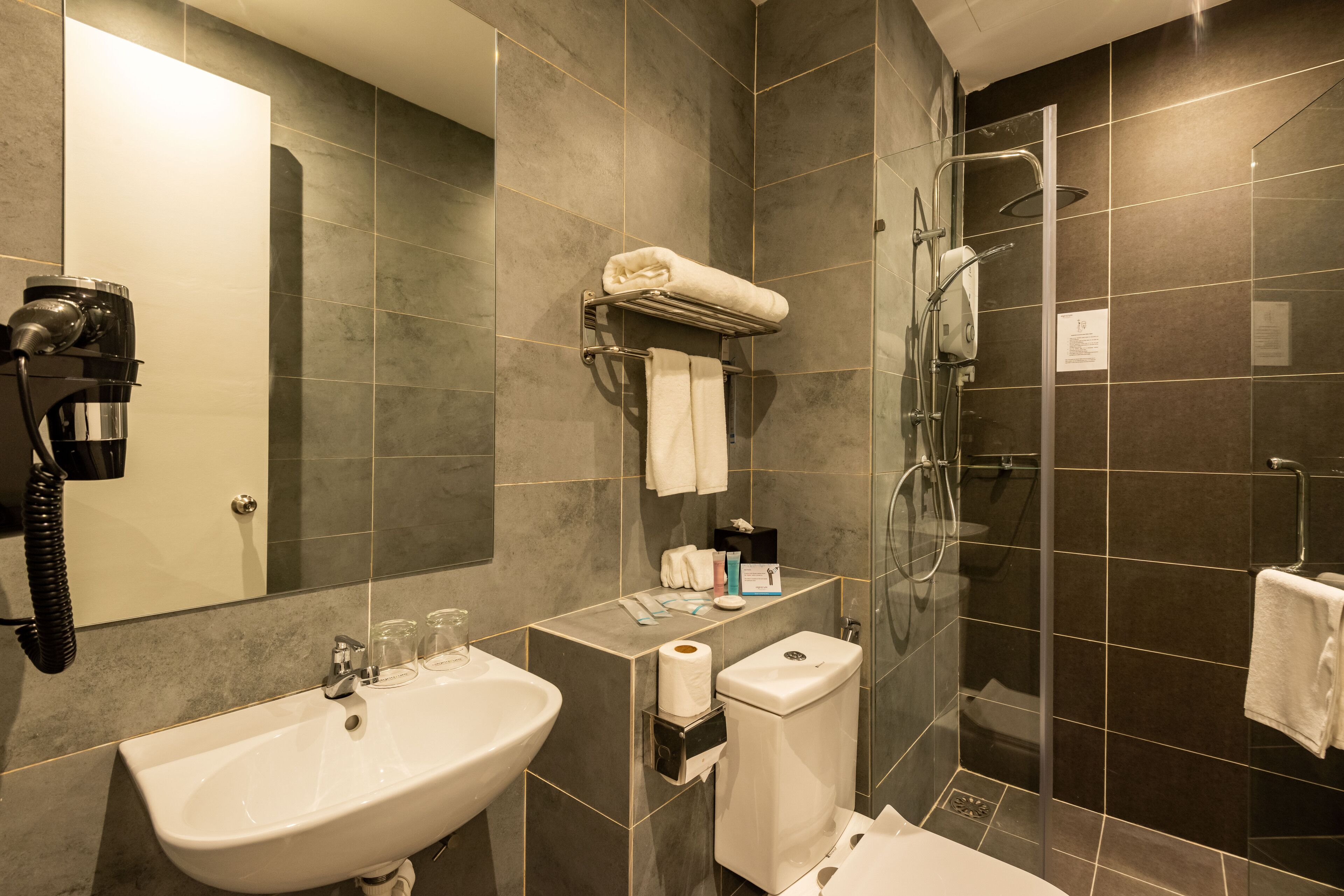 Un baño moderno con lavamanos, inodoro y ducha.