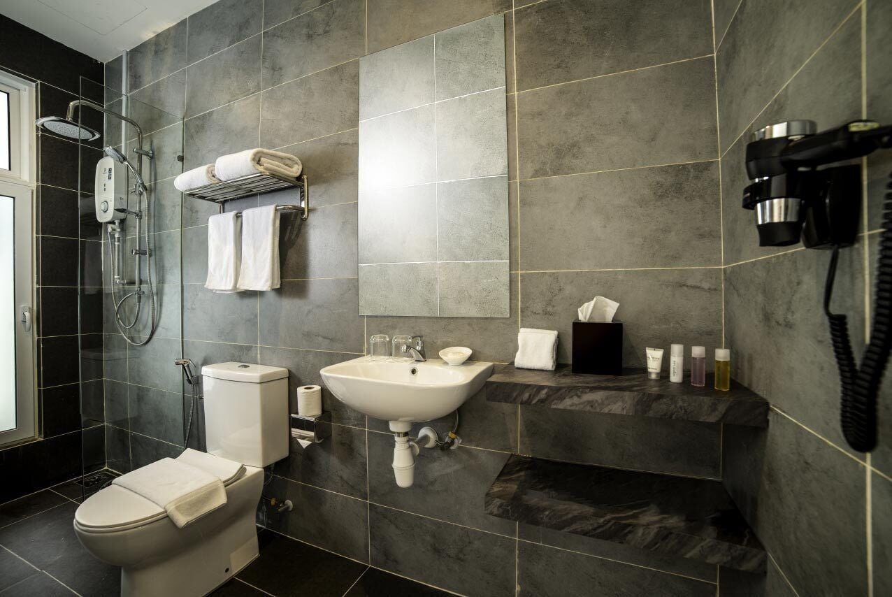 A modern bathroom with a toilet, sink, and shower. There are towels and toiletries on the counter.