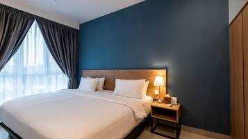 A hotel room with a large bed, a nightstand with a lamp, and a view of the city through the window.