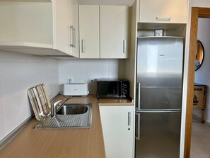 A compact kitchen with a stainless steel refrigerator, a toaster, and a microwave.