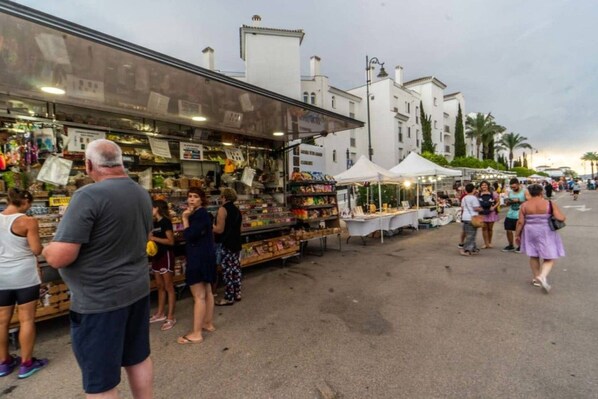 A street market with various stalls and people shopping.