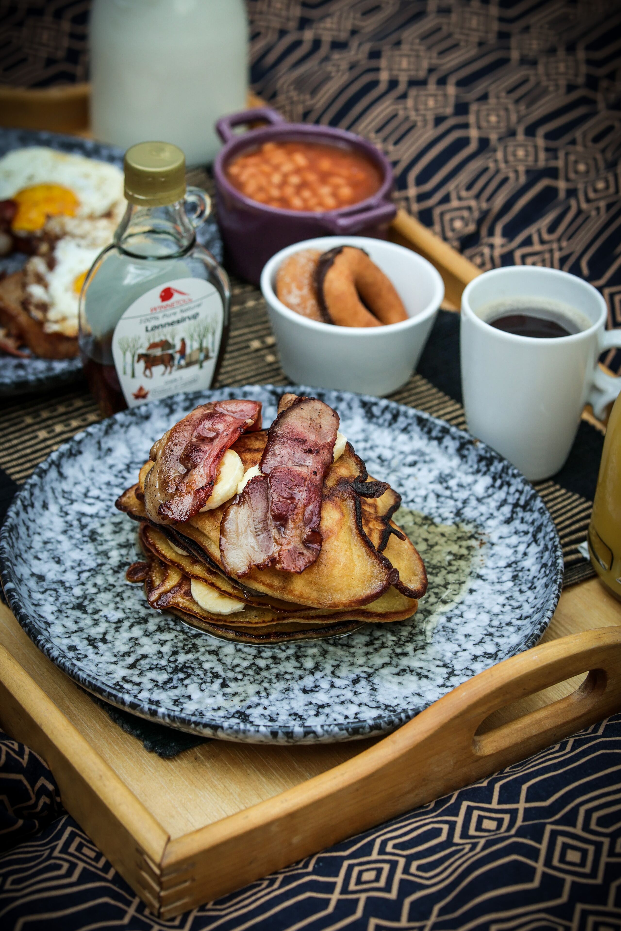 A breakfast plate with bacon, eggs, and toast, accompanied by a coffee cup and a bottle of milk.
