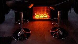 Una habitación con chimenea, un piano y vistas a montañas nevadas a través de un ventanal grande.