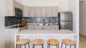 A modern kitchen with a central island, stainless steel appliances, and a mosaic backsplash. - Aguada Ocean Club 3A - 2 Bed 1 Bath Suite (Aguada)