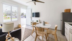 Una cocina moderna con comedor, ventilador de techo, televisor y refrigerador.