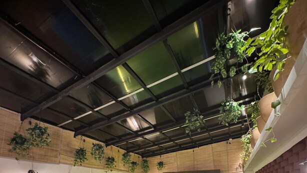 A hot tub area with a wooden deck, steps leading to the tub, and hanging plants. - Shanti Inn Dormitory (Varanasi)