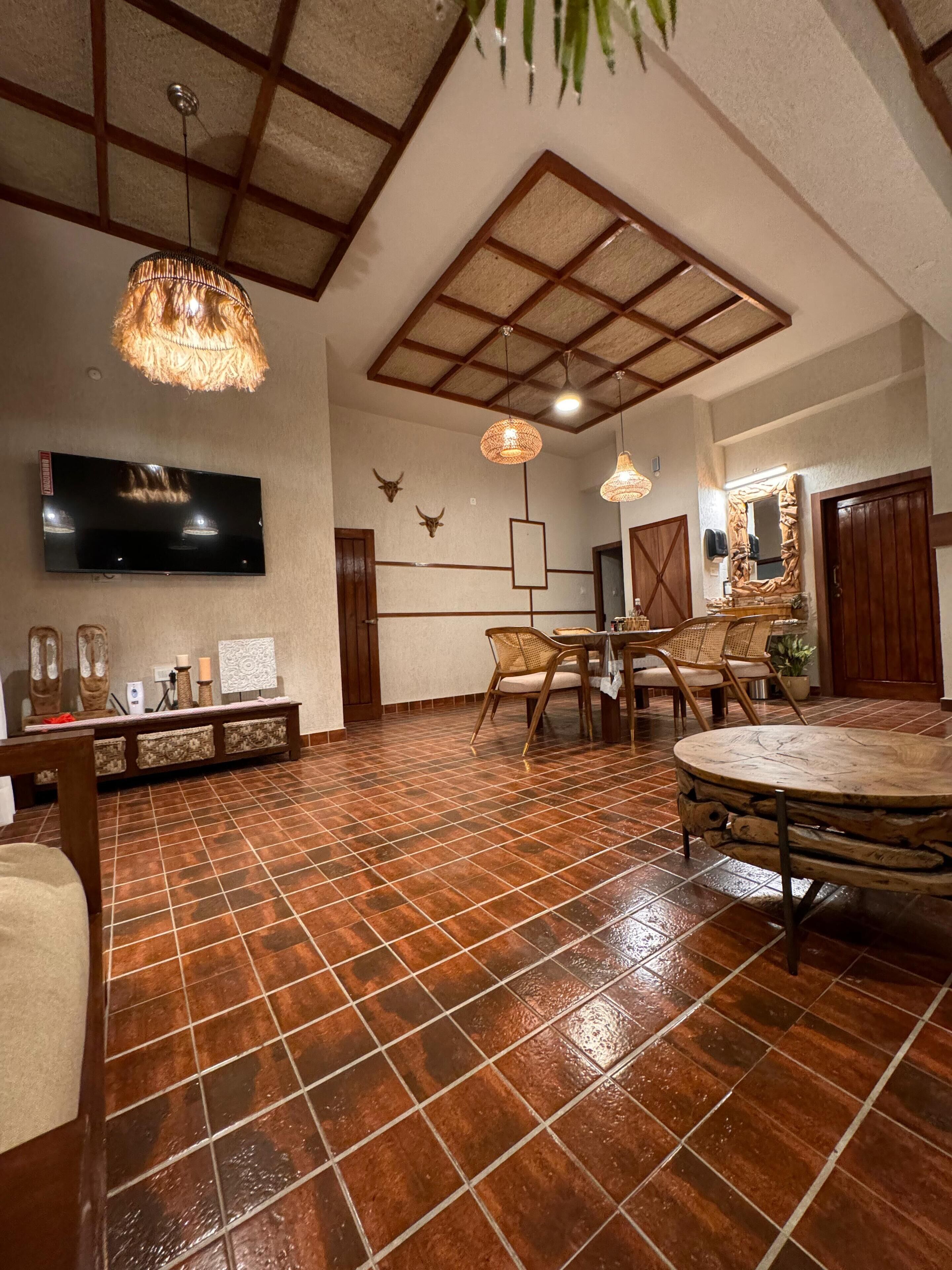 A spacious living area with a large TV, rustic decor, and a tiled floor.