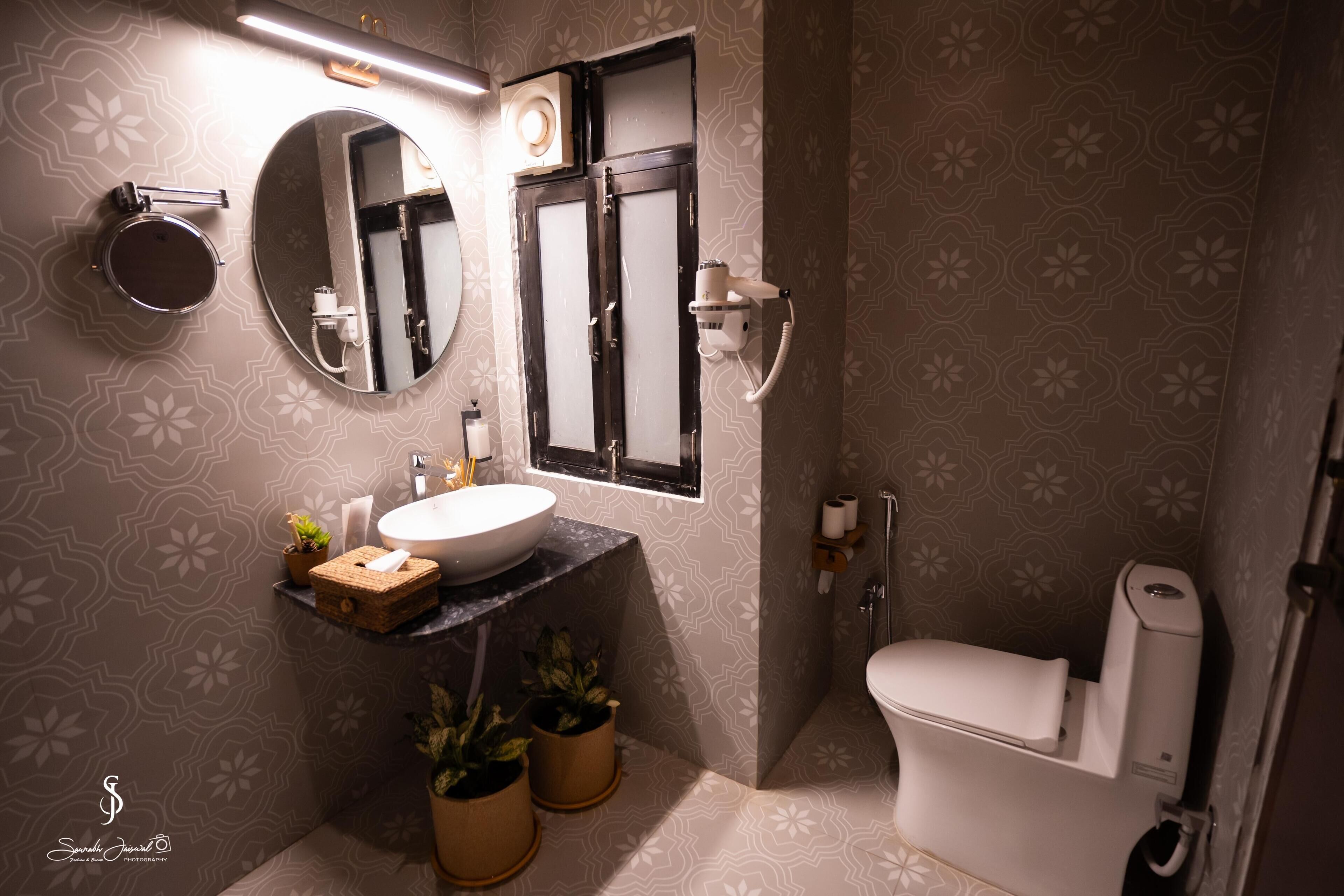 A bathroom with a round mirror, a sink, a toilet, and a shower area.
