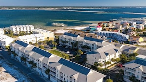 Un hôtel situé sur la côte, composé de plusieurs bâtiments à étages, avec une plage et une jetée en arrière-plan.