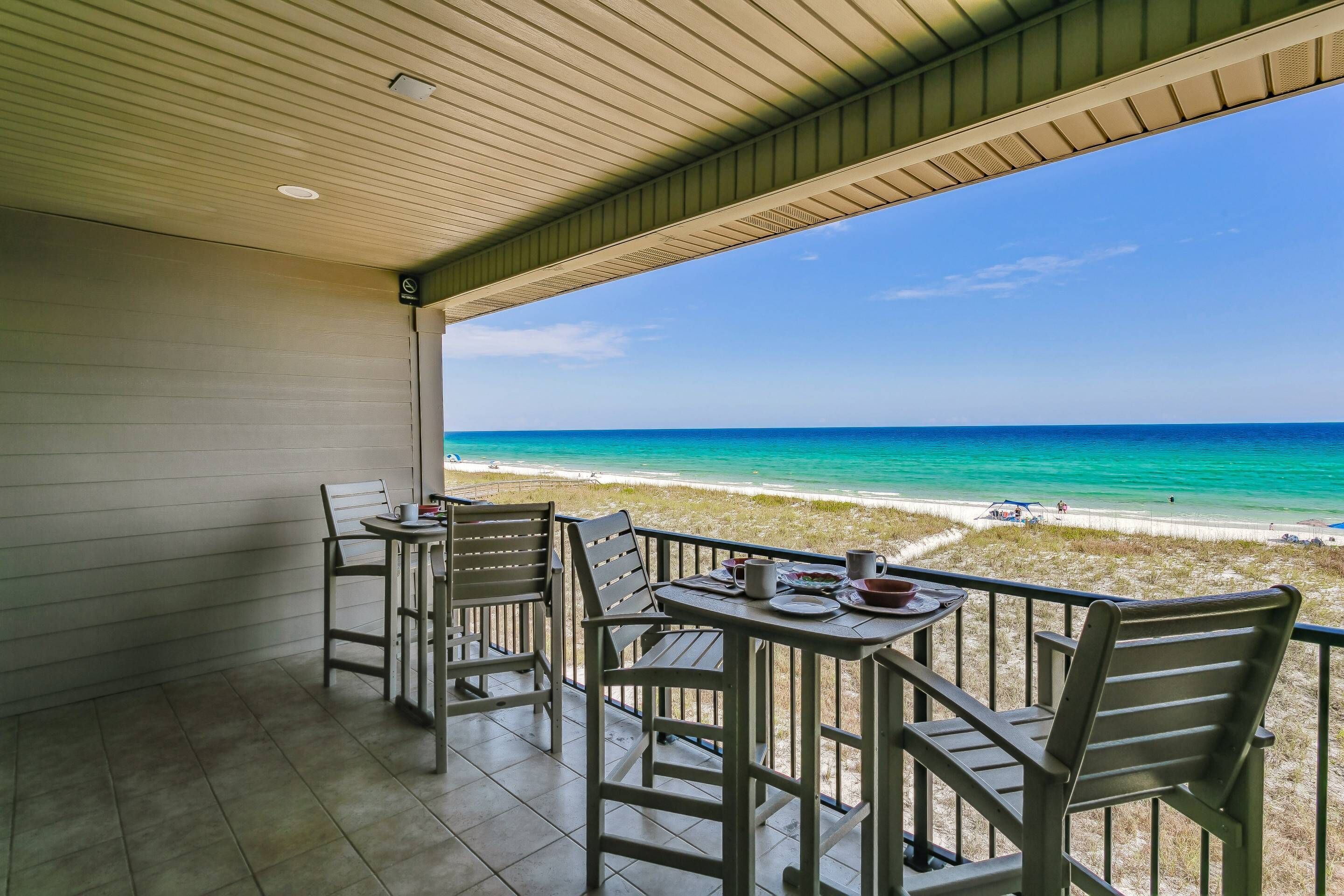 A covered outdoor seating area with a view of the beach.