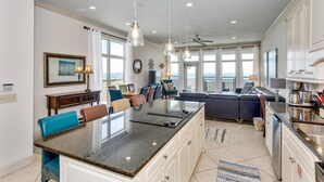 A spacious kitchen with a large island, white cabinetry, and a view of the ocean. - Luxurious Beachfront End Unit Townhome |Unobstructed Gulf Views |Step onto Sugar White Sands |Garage (Navarre Beach)